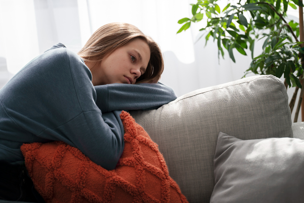 Pensive young woman on a couch, between visits